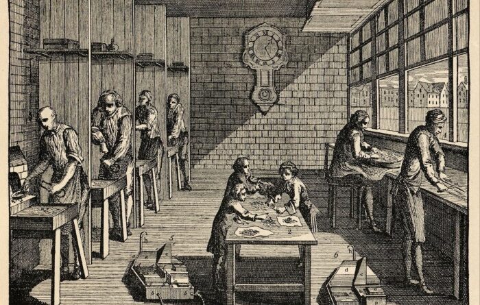 A black and white photograph of people working on benches in a letter founder's workhouse, circa 1750, which appeared in Universal Magazine.